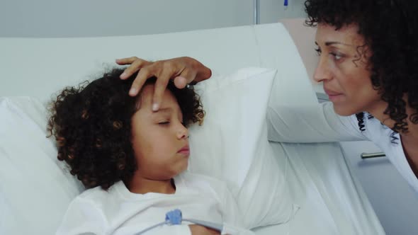 Front view of African american mother talking with her son in ward at hospital 