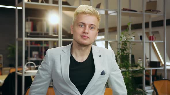 Young Man Standing in Contemporary Office Room and Posing on Camera