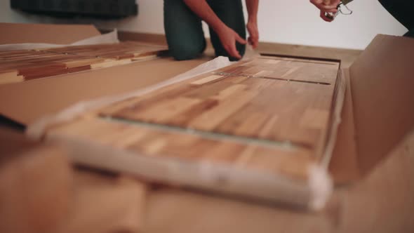 Measuring A Piece Of Wood Panel After Unboxing For DIY Table Assembly. close up