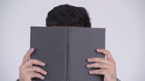 Young Indian Nerd Man Covering Face with Book