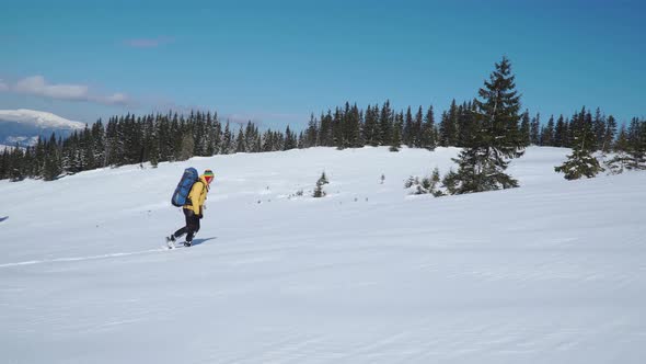 A Man with a Backpack Travels in the Mountains in Winter