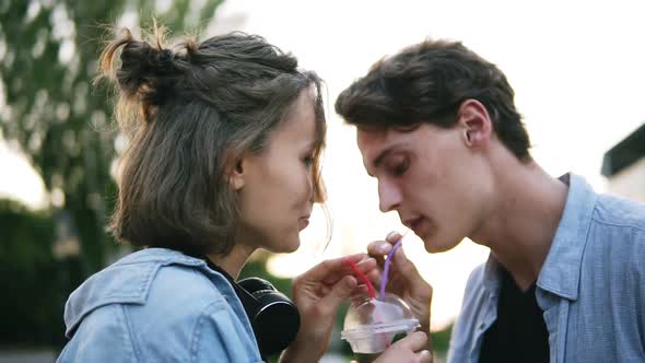 Young Attractive Couple are Drinking From a Plastic Cup Together