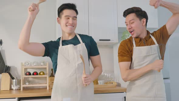 Asian happy handsome man gay couple sing and dance together in kitchen.