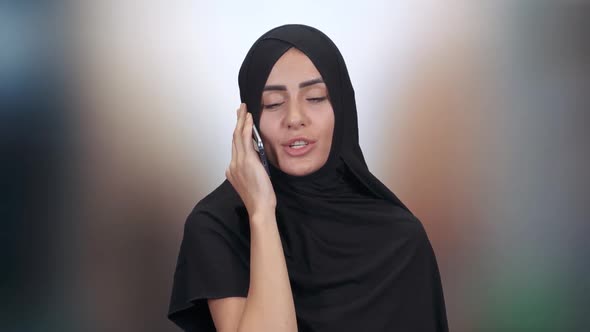 Portrait of a Beautiful Muslim Woman, a Female in a Hijab Communicates and Talks on a Mobile Phone