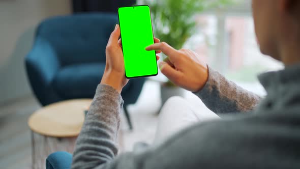 Woman at Home Using Smartphone with Green Mockup Screen in Vertical Mode