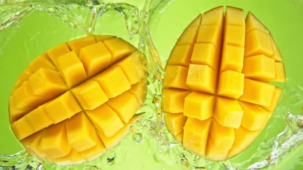 Super Slow Motion Shot of Mango Falling and Splashing Into Water on Green Background at 1000Fps.