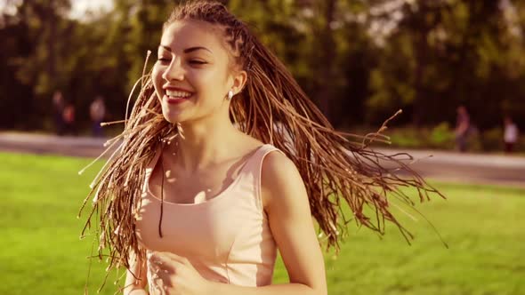Long Hair Woman with Dreads Running in Park and Turning Her Head Around Playing with Her Dreads