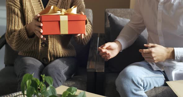 Cropped Frame Manle Hands Hold Cardboard Decorated Festive Red Box with Yellow Ribbon Girl Woman