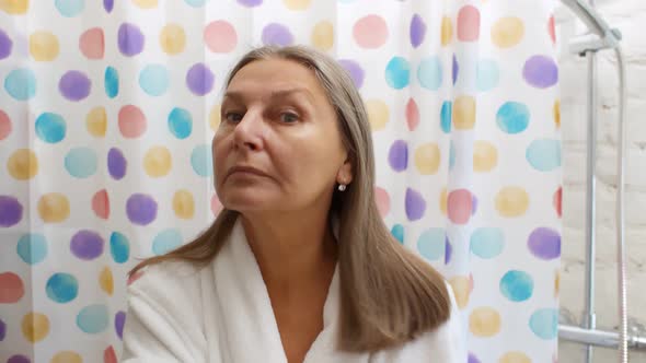 Portrait of Senior Woman Brushing Hair in Bathroom