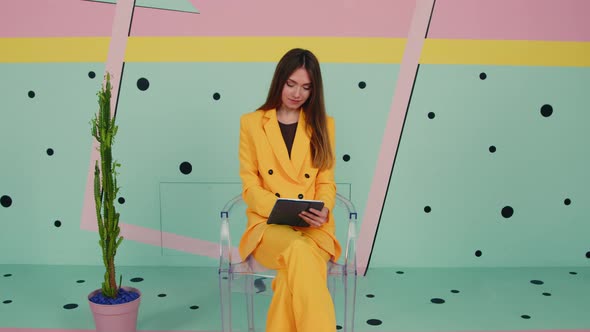 Woman In Yellow Suit Uses Tablet Computer