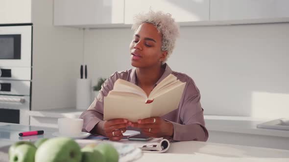 Young African American Woman Reading Book at Breakfast and Dream About Future