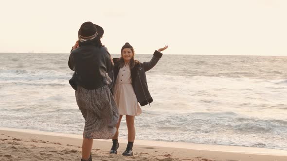 Couple of Beautiful Young Women Walking on the Beach on at Sunset