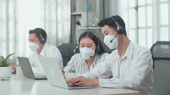 A Woman Of Three Call Centre Agents Wearing Mask And Helping A Man To Work With Computer