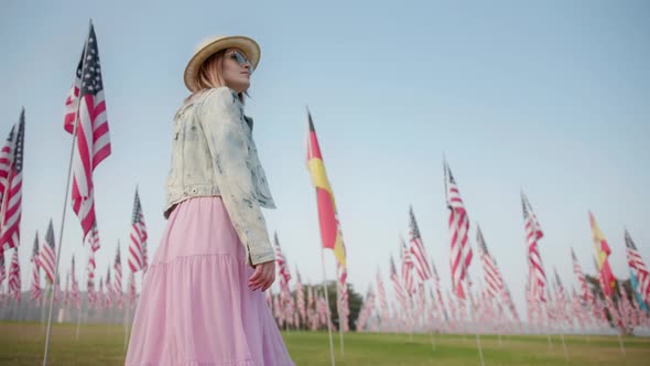 Stylish Woman Walking in Memorial Park with Many American and German Flagpoles