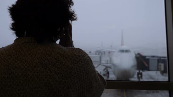 Silhouette of Male Passenger Talking on Phone at Airport