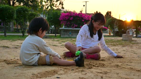 Asian Children Playing Sand In Playground Under Sunset