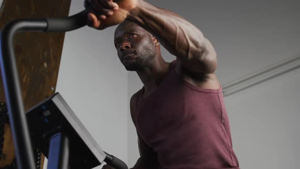 Fit african american man exercising on training bike inside gym