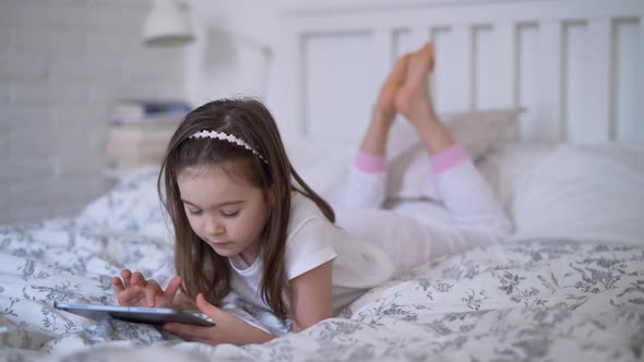 Girl in Pajama Playing Videogame on Tablet