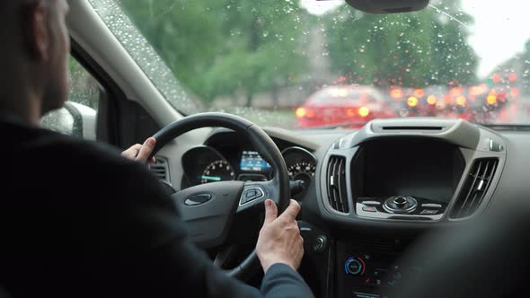 Man Drives a Car Along the Road in the City During the Rain