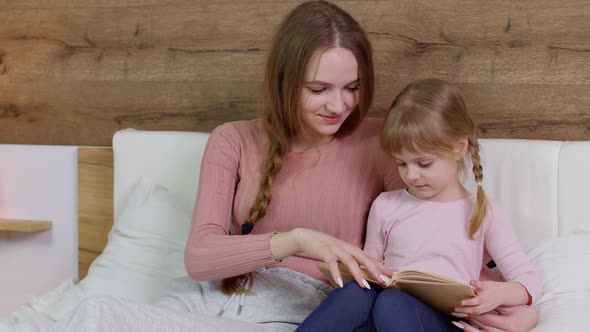 Young Mother Reading Goodnight Story Book Fairytale to Child Daughter Kid Girl in Night Bedroom