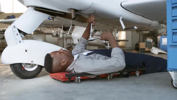 Black Mechanic Repairing Airplane in Hangar