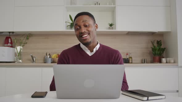 Happy Smiling African American Man Greeting His Friends on a Video Call on a Laptop at Home Interior