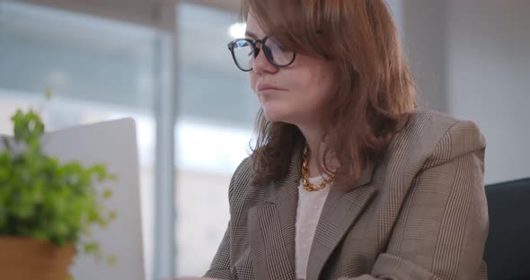 Beautiful Businesswoman Sitting at Desk and Using Laptop While Working in Office