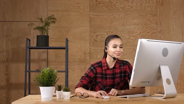 Beautiful Freelancer Female Talking in a Video Conference on Line with a Headset with Microphone