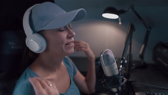 Beautiful Woman In A Cap And White Headphones Leads A Live Stream