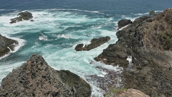 Tourists on Summit Admiring Beautiful Waters with Strong Waves Splashing Against Rocks, Indonesia