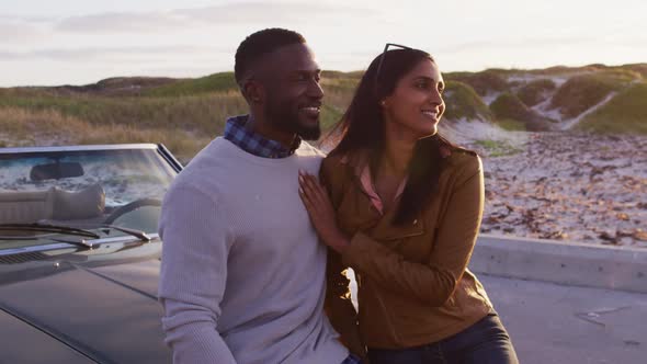 African american couple embracing each other while standing near the convertible car on the road