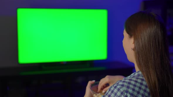 Young Woman Sits on an Armchair and Watches TV