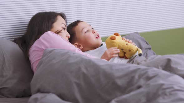 Handsome Asian mother and son talking and lying on the bed