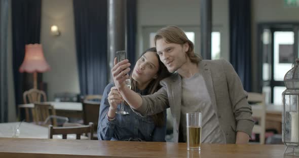 Friends taking self photograph and talking in pub