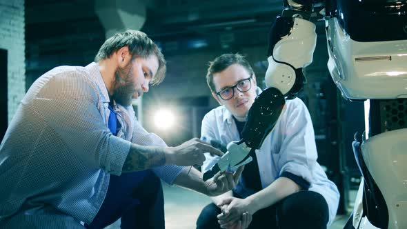 Two Specialists Carefully Examining a Futuristic Robot