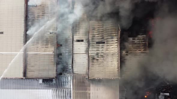 Aerial view fire hose spray water at the burning happen at factory