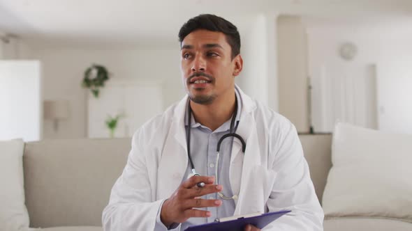 Portrait of happy hispanic male doctor having interview with patient at home