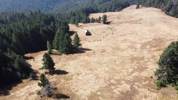 Drone Flying Over A Field In a Forested Area With A Barn