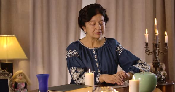 Portrait of Caucasian Mature Woman Sitting at the Table and Reading Cards