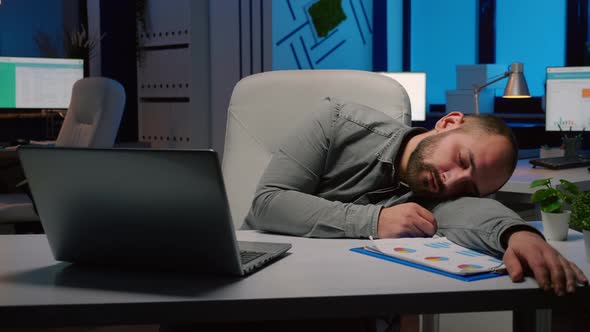 Exhausted Overworked Businessman Sleeping on Desk Table in Startup Business Office