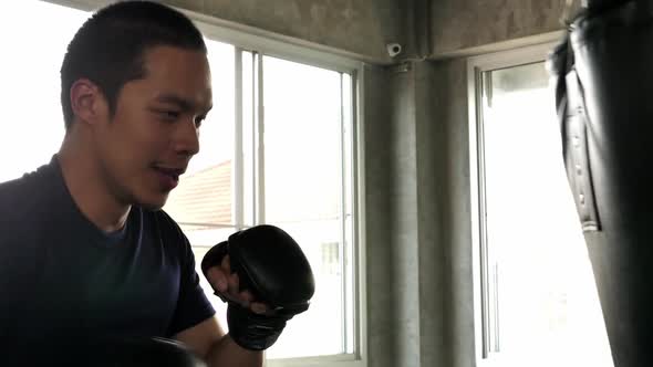 Sportsman hitting punching bag during boxing practice in fitness gym