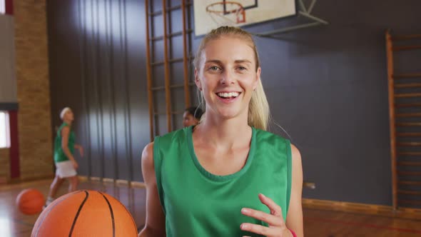 Portrait of caucasian female basketball player with teammates in background