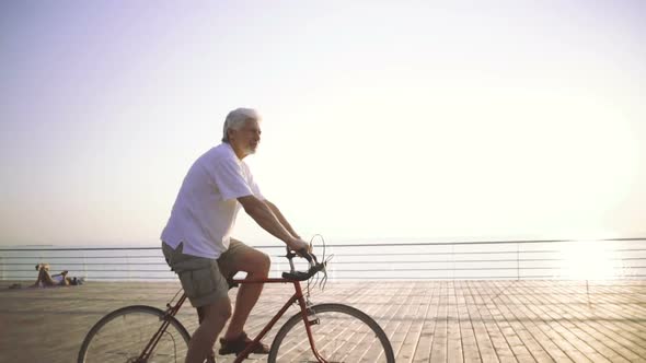 Handsome Senior Man Riding Bike on Seafront Slow Motion