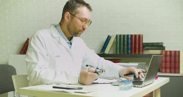 A Doctor Writes a Report in His Office