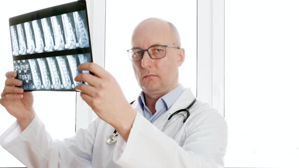 Man Surgeon Looking Backbones X-ray Front Window in Clinic Office. Male Doctor Holding X-ray Spine