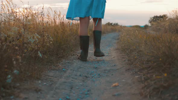 Little Girl in Rubber Boots Run in a Field in the Countryside