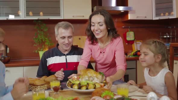 Young Woman Putting Dish with Baked Chicken on Dinner Table Served for Birthday Celebration in