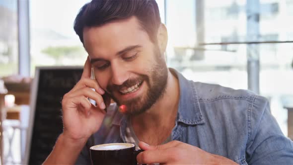 Man talking on mobile phone while having coffee