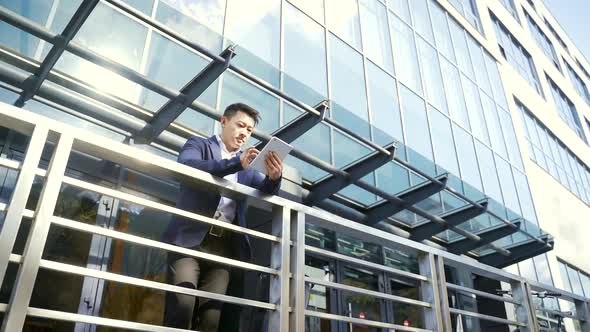 young asian businessman standing near the railing of terrace a modern office building