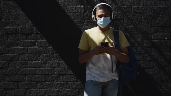 Mixed race man wearing face mask and using smartphone in the street
